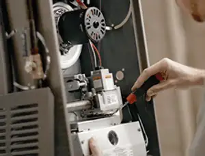 Furnace repair technician inspecting internal components and wiring in Duluth, MN