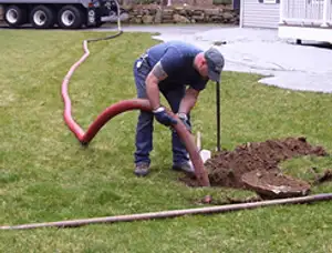 Septic pumping technician servicing a residential septic tank with a vacuum hose in Duluth, MN