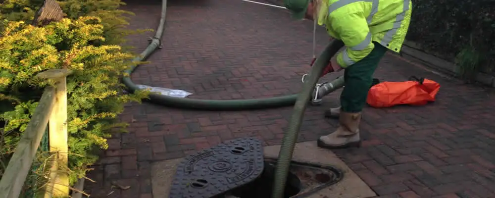 Septic tank cleaning technician servicing a septic tank with a vacuum hose in Duluth, MN