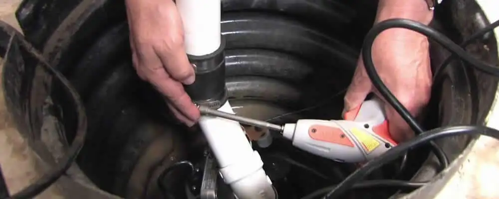 Sump pump installation technician connecting PVC discharge piping in Duluth, MN